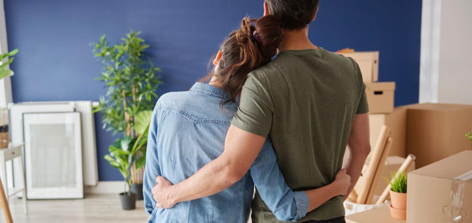 A couple embracing whilst looking towards some moving boxes