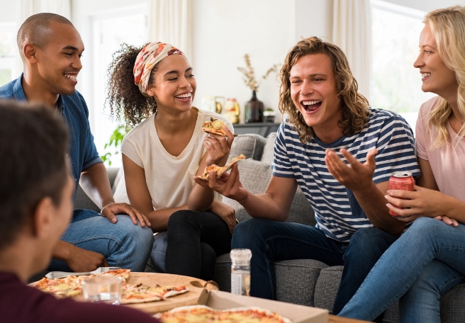 A group of friends laughing and eating pizza together