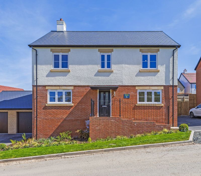 Modern two-story detached home with red brick and white stucco exterior, garage, landscaped front garden, and a stylish black front door.