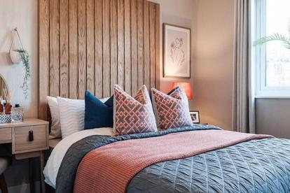 An example of an interior designed bedroom with floor to ceiling wooden slat headboard and pink and grey bedding.