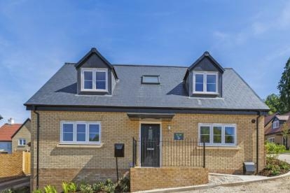 Modern two-story detached home with light brick exterior, dark slate roof, dormer windows, landscaped front garden, and central black front door at Coppice View..
