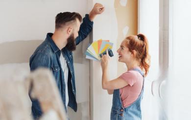 Two people looking at a colour swatch fan in front of a plain wall