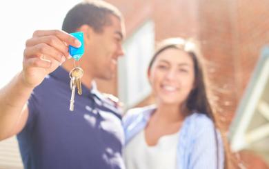 A couple stood outside a house in an embrace holding keys