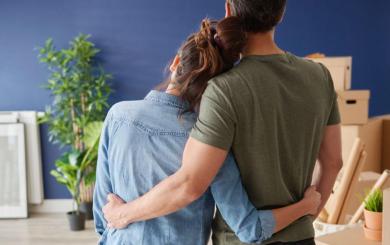 A couple embracing whilst looking towards some moving boxes