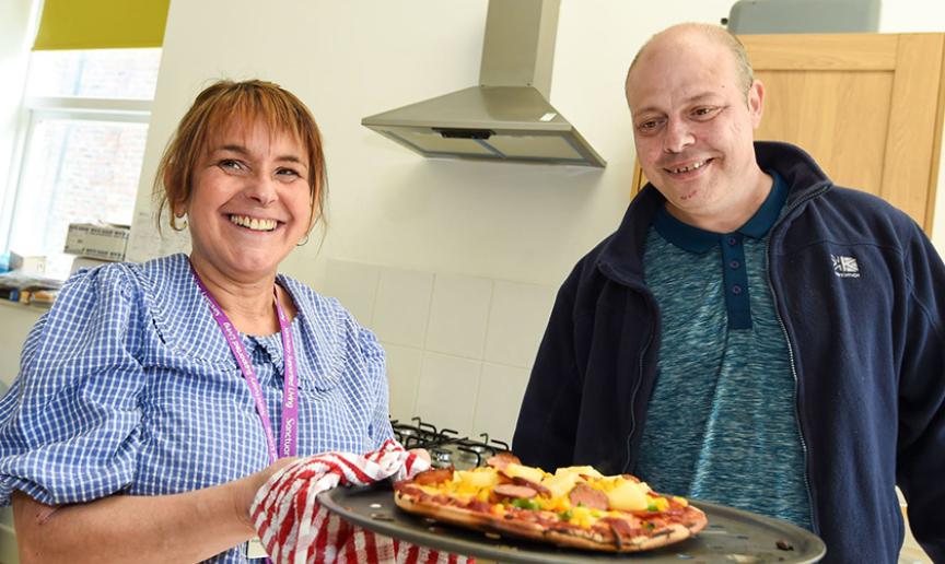 Staff and service user cooking pizzas together