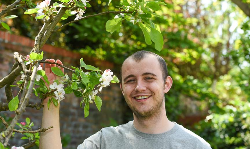 Supported Living resident smiling next to a tree