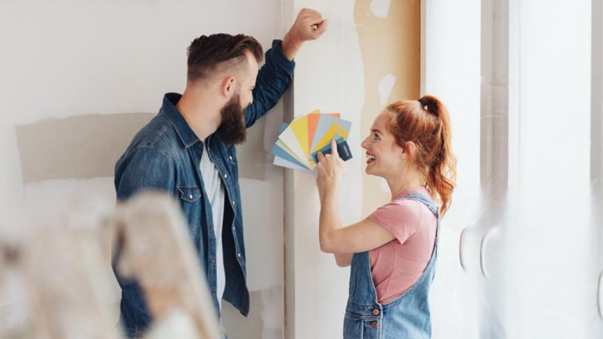 Two people looking at a colour swatch fan in front of a plain wall