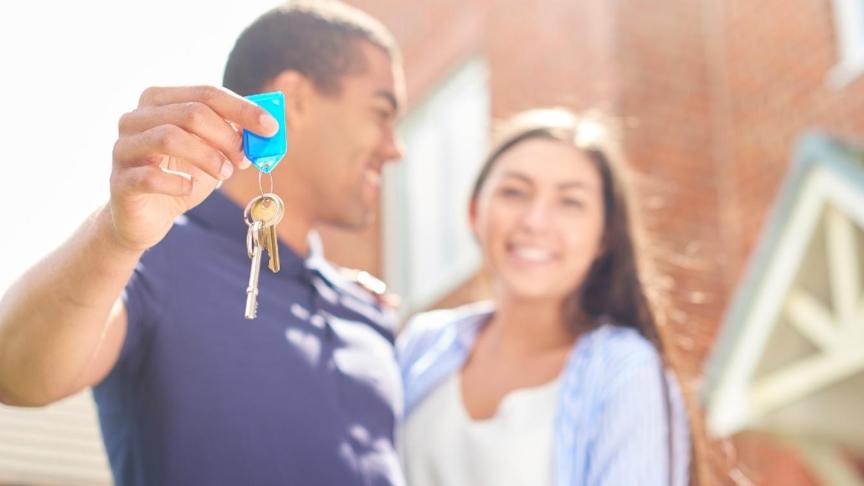 A couple stood outside a house in an embrace holding keys