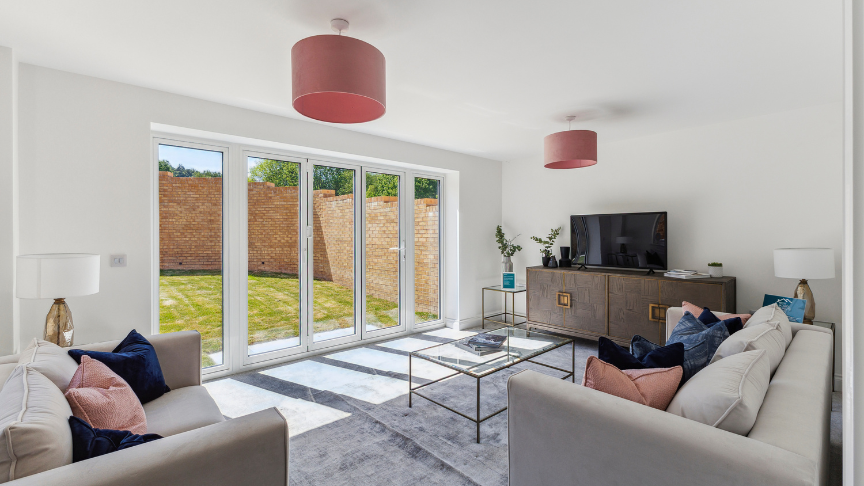 A new-build living room with white walls, patio doors leading to a sunny garden and stylish furniture inside