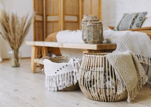A cozy room featuring a bed, a wooden table, and a basket, creating a warm and inviting atmosphere.